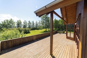 Una terraza de madera con vistas a un área con césped y árboles.
