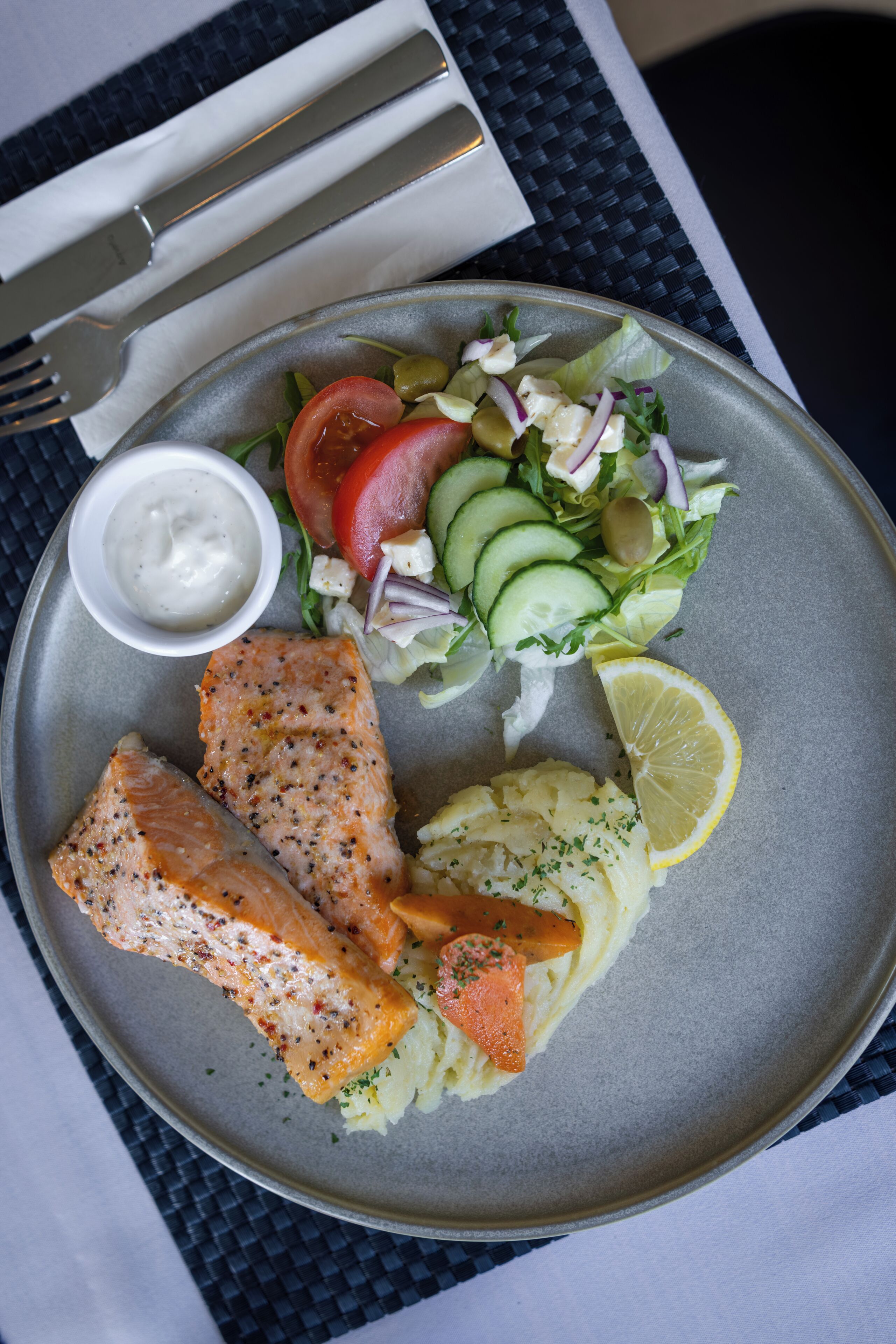 A plate with salmon, a salad, and mashed potatoes.