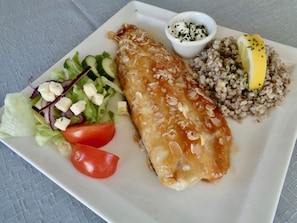 Une assiette contenant un filet de poisson, une salade et des céréales.