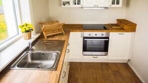 A kitchen with white cabinets, a wooden countertop, a built-in oven, and a window with a view of greenery.