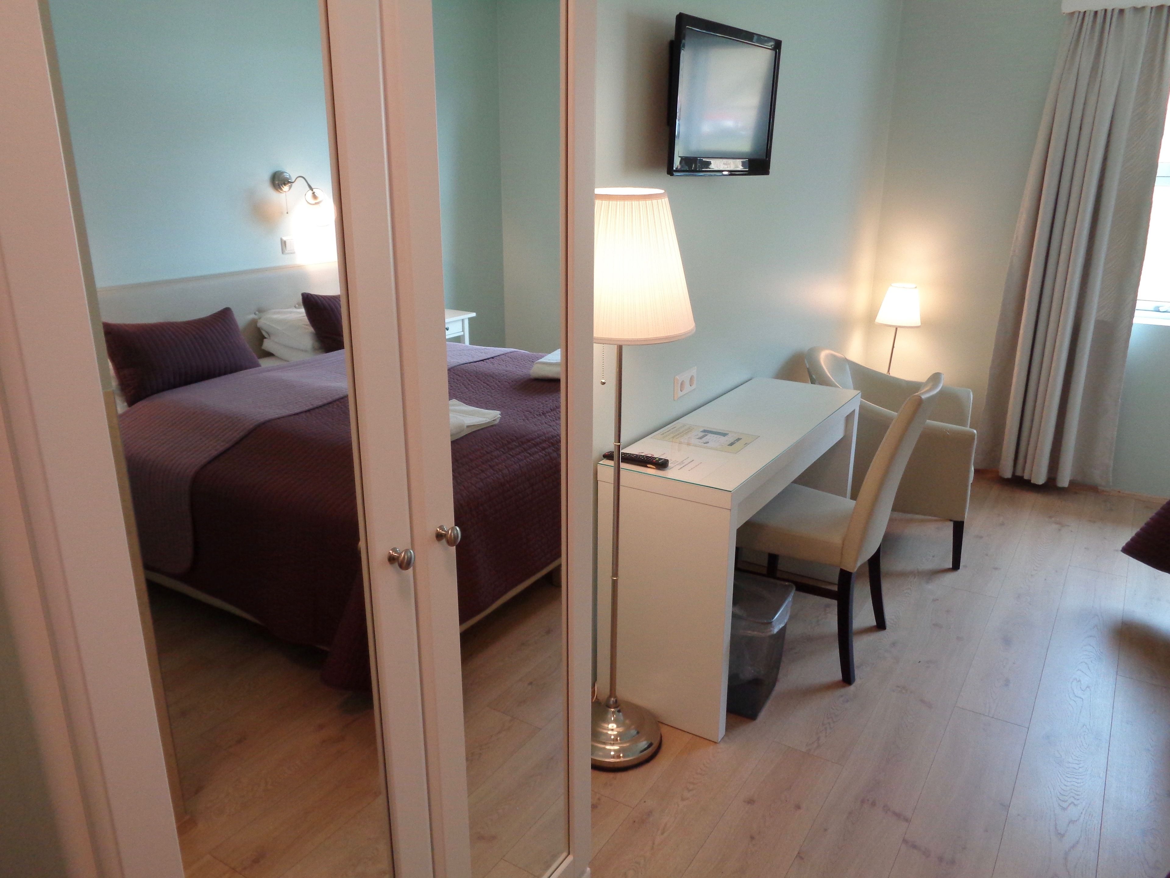 Une chambre d’hôtel avec un lit, un bureau, deux chaises, une télévision et une lampe.