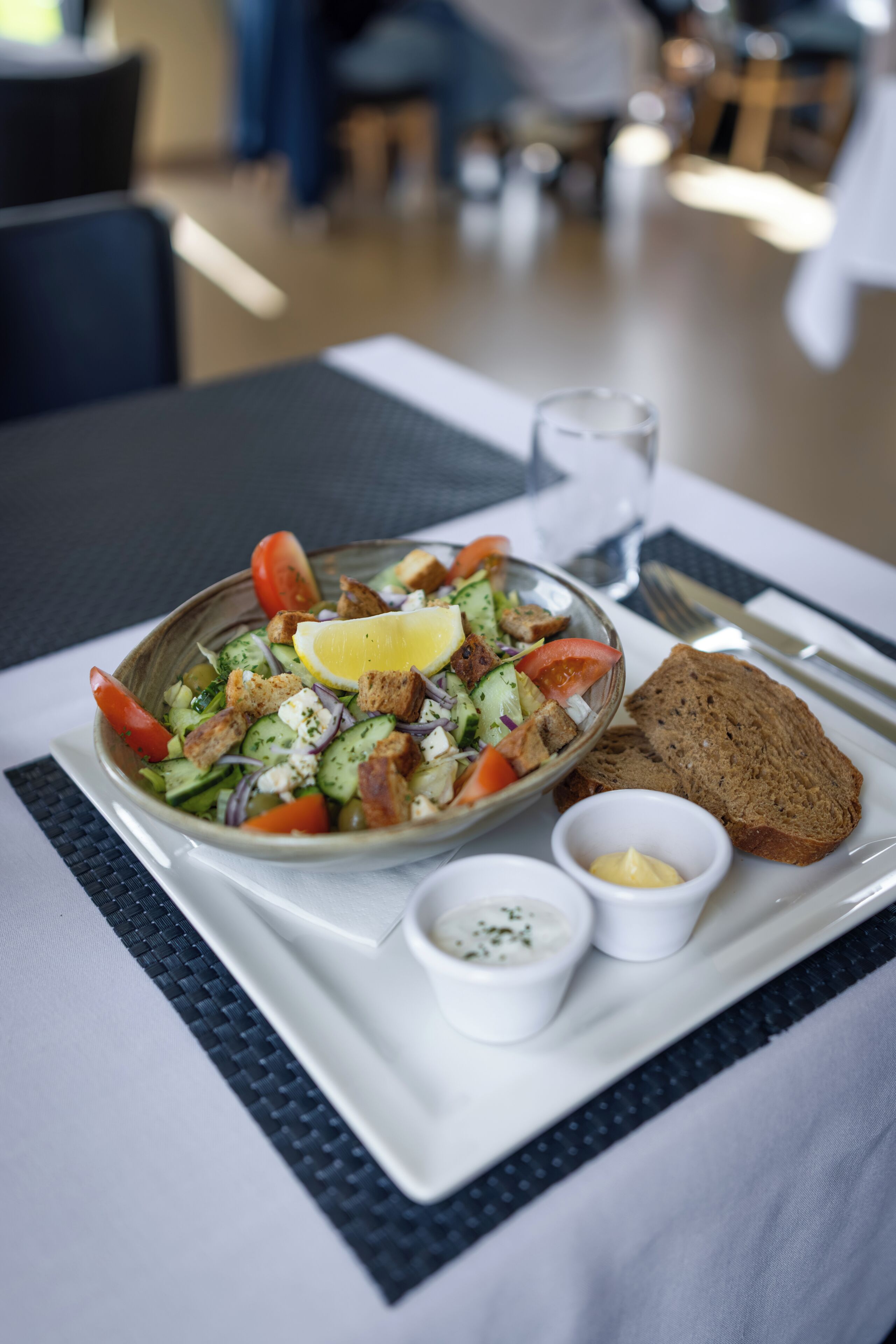 Un repas composé d’une salade, de pain et de condiments, servi sur un plateau.