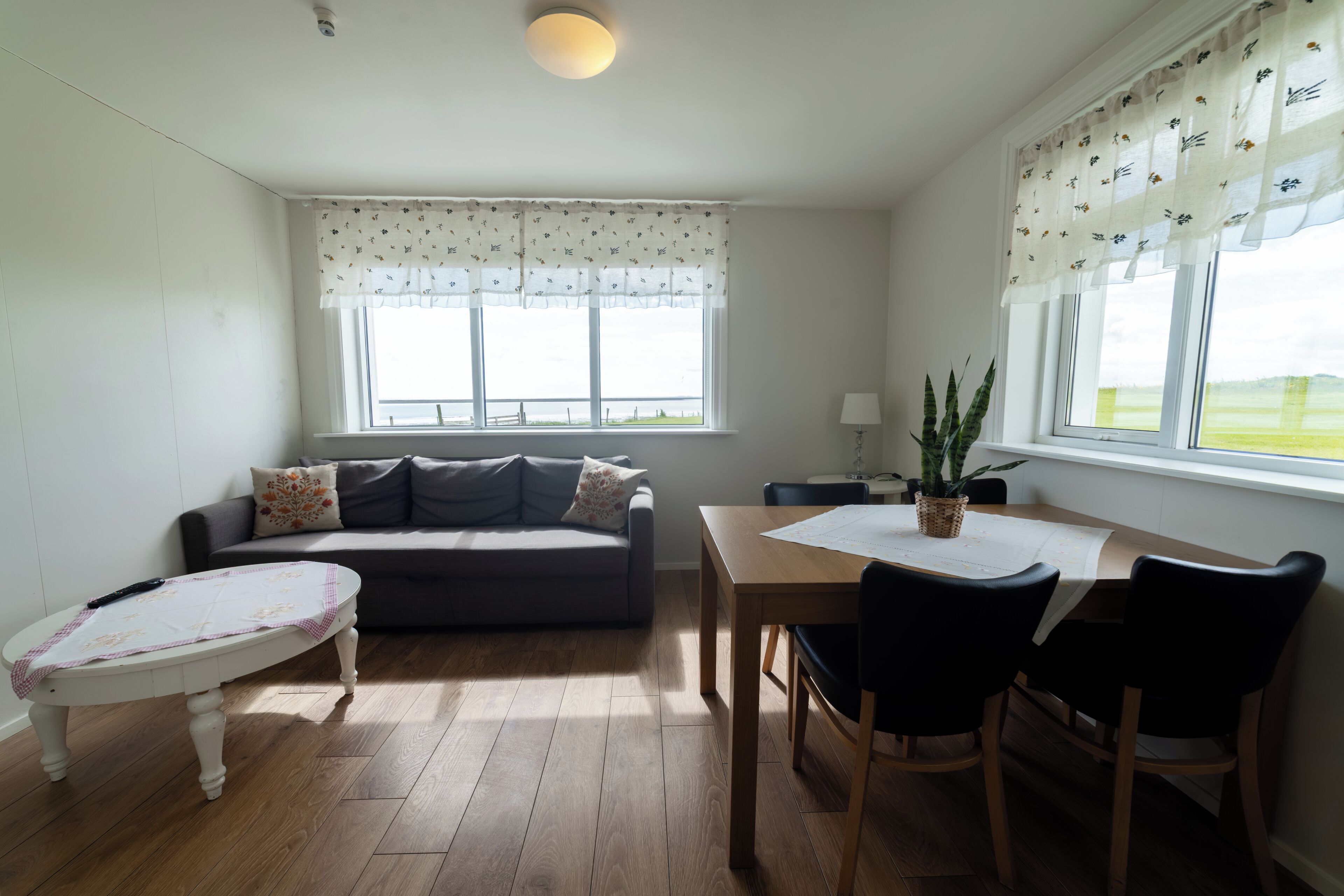 Una habitación con sofá, una mesita y una ventana con vistas al exterior.