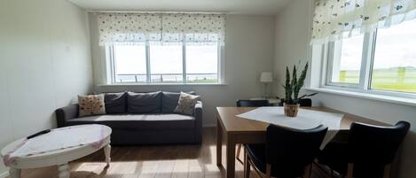 Una habitación con sofá, una mesita y una ventana con vistas al exterior.