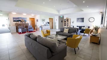 Eine großzügige Lobby mit Empfangstresen, einer Sitzecke mit Sofas und Sesseln sowie einer Kaffeestation.