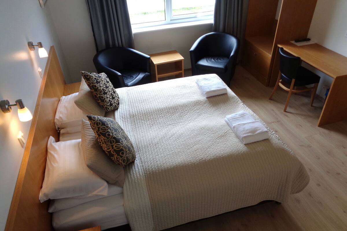 Ein Hotelzimmer mit einem Bett, zwei Stühlen, einem Schreibtisch und einem Fenster.
