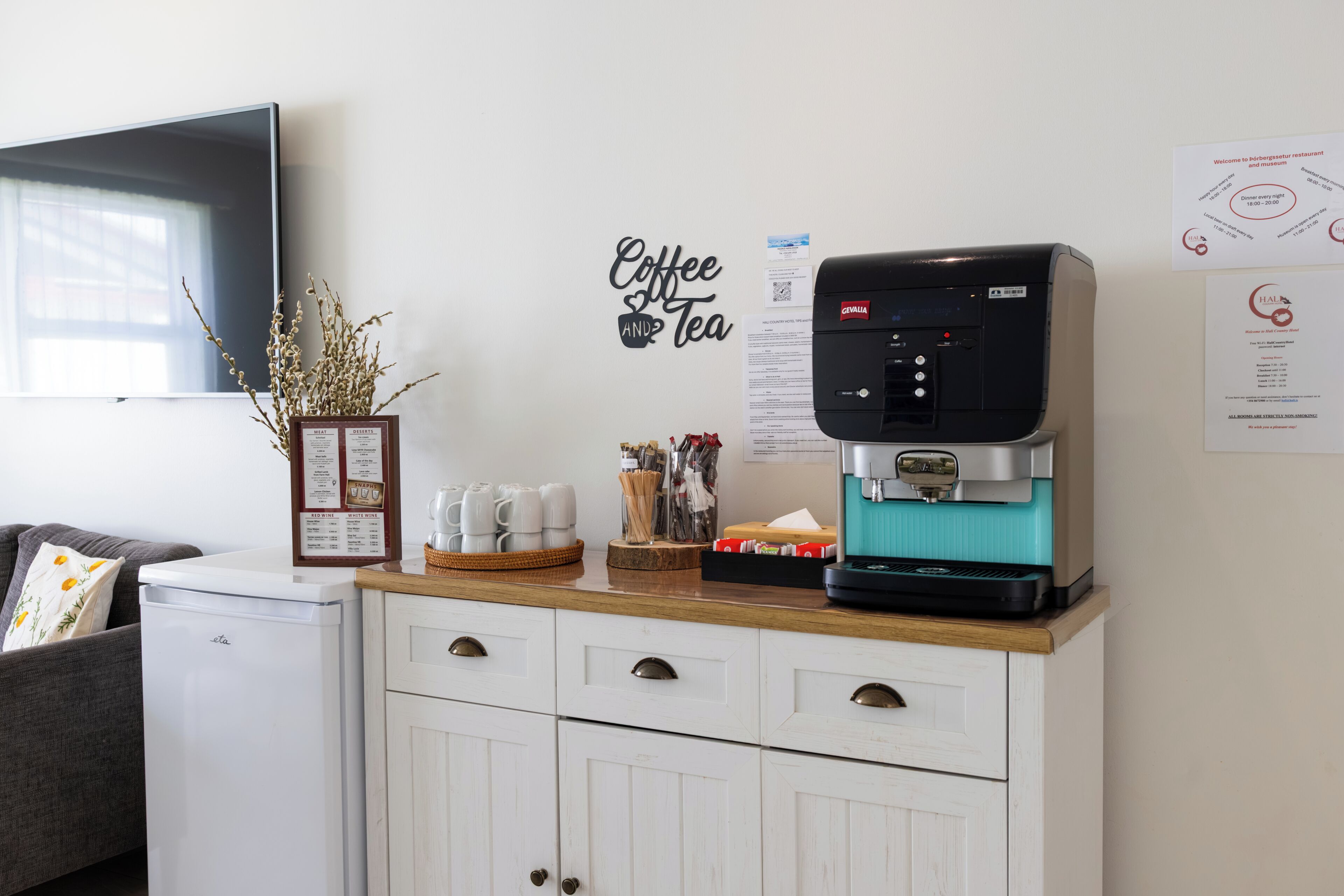 A coffee station with a coffee machine, a menu board, and a wall decoration.