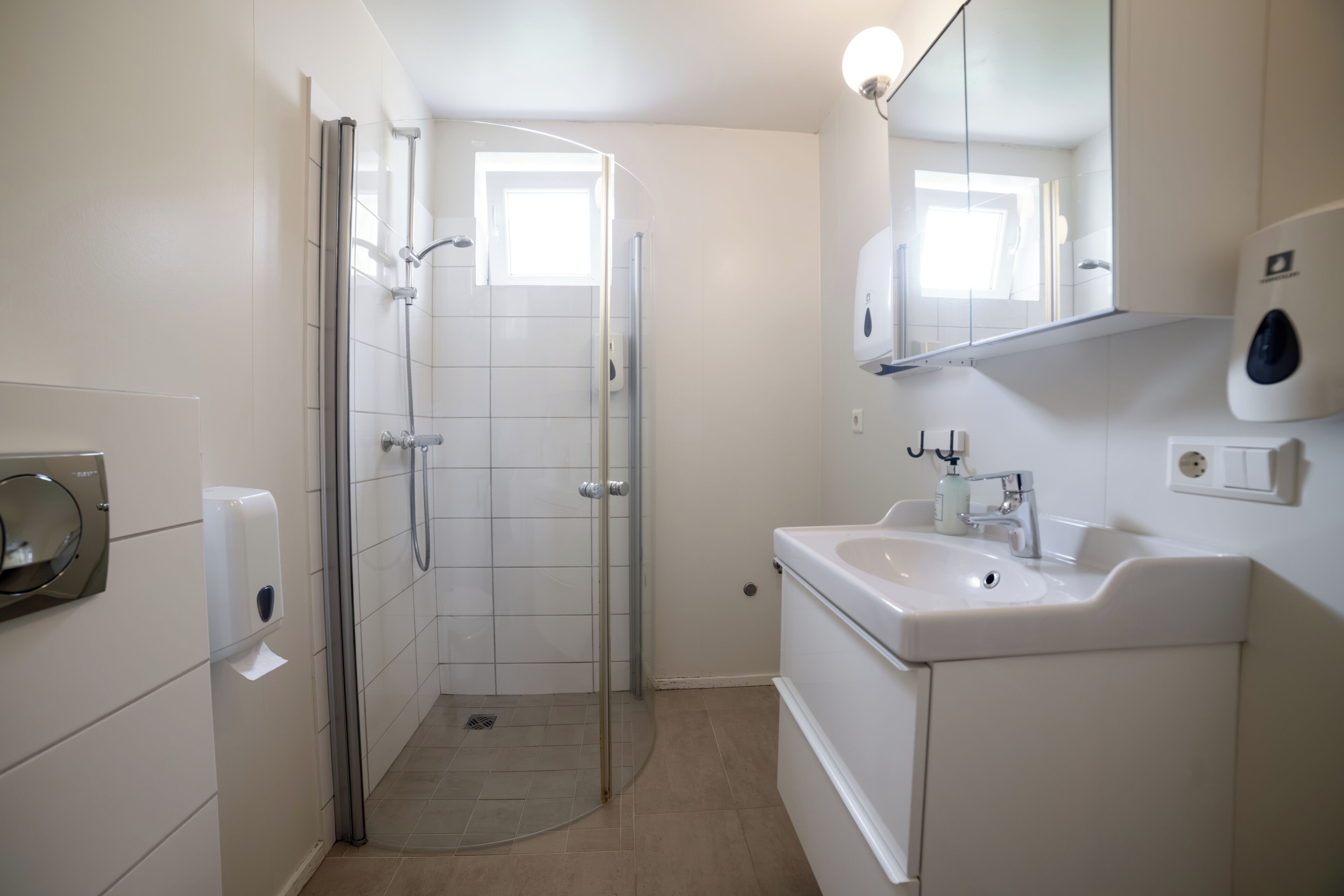 Baño con ducha, inodoro, lavabo y espejo.