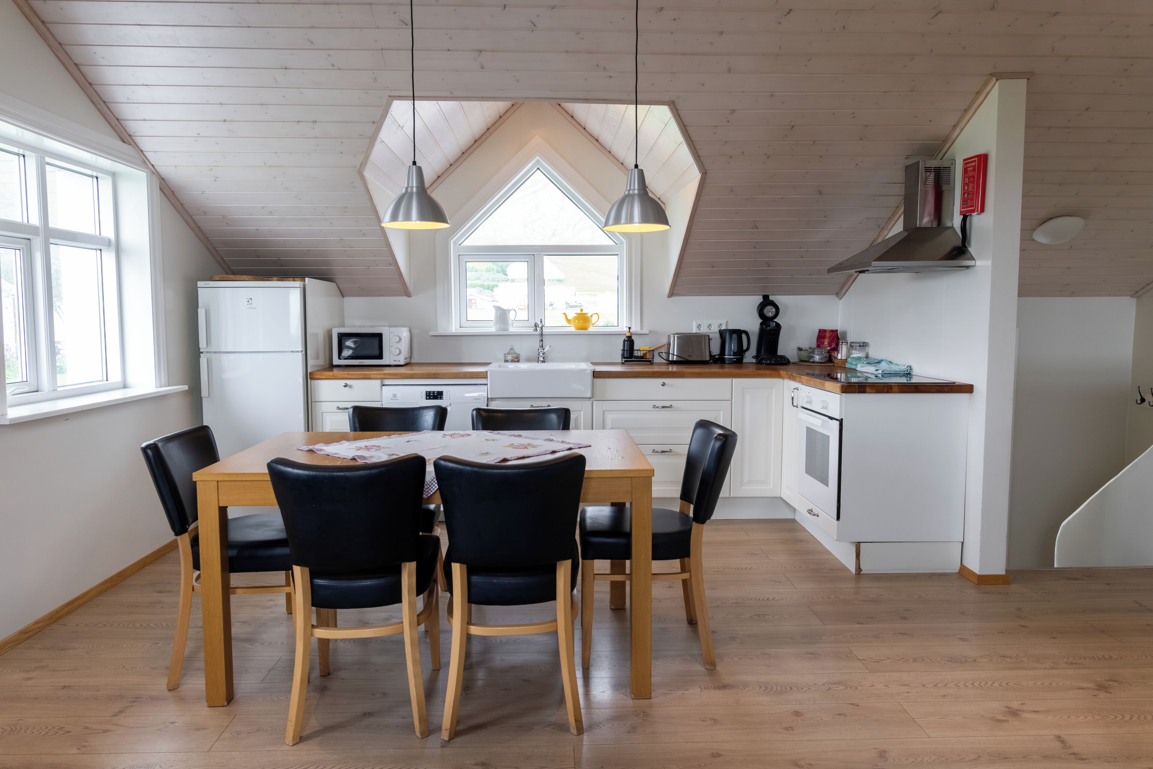 A modern kitchen with a dining area, featuring a wooden table, chairs, and pendant lighting.