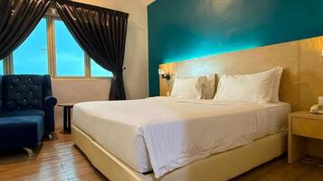 A hotel room with a large bed, a chair, a nightstand, and a window with curtains.