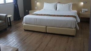 A hotel room with a large bed, a small round table, a chair, a nightstand, and a wall-mounted light fixture. - Summit Signature Hotel Batu Pahat (Batu Pahat)