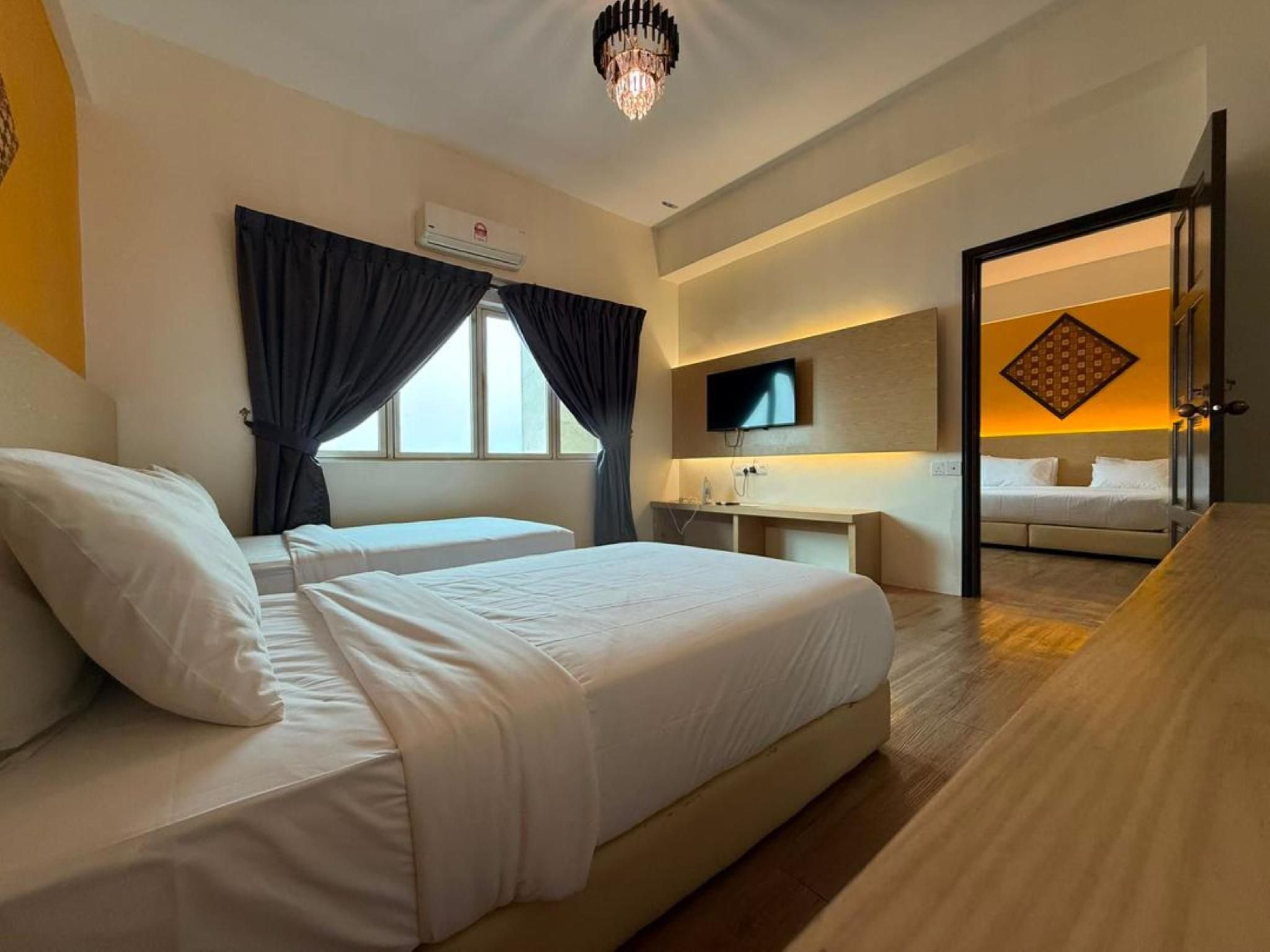 A hotel room with two beds, a TV, a desk, and a bathroom visible through an open door.