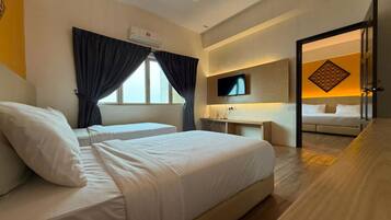A hotel room with two beds, a TV, a desk, and a bathroom visible through an open door.