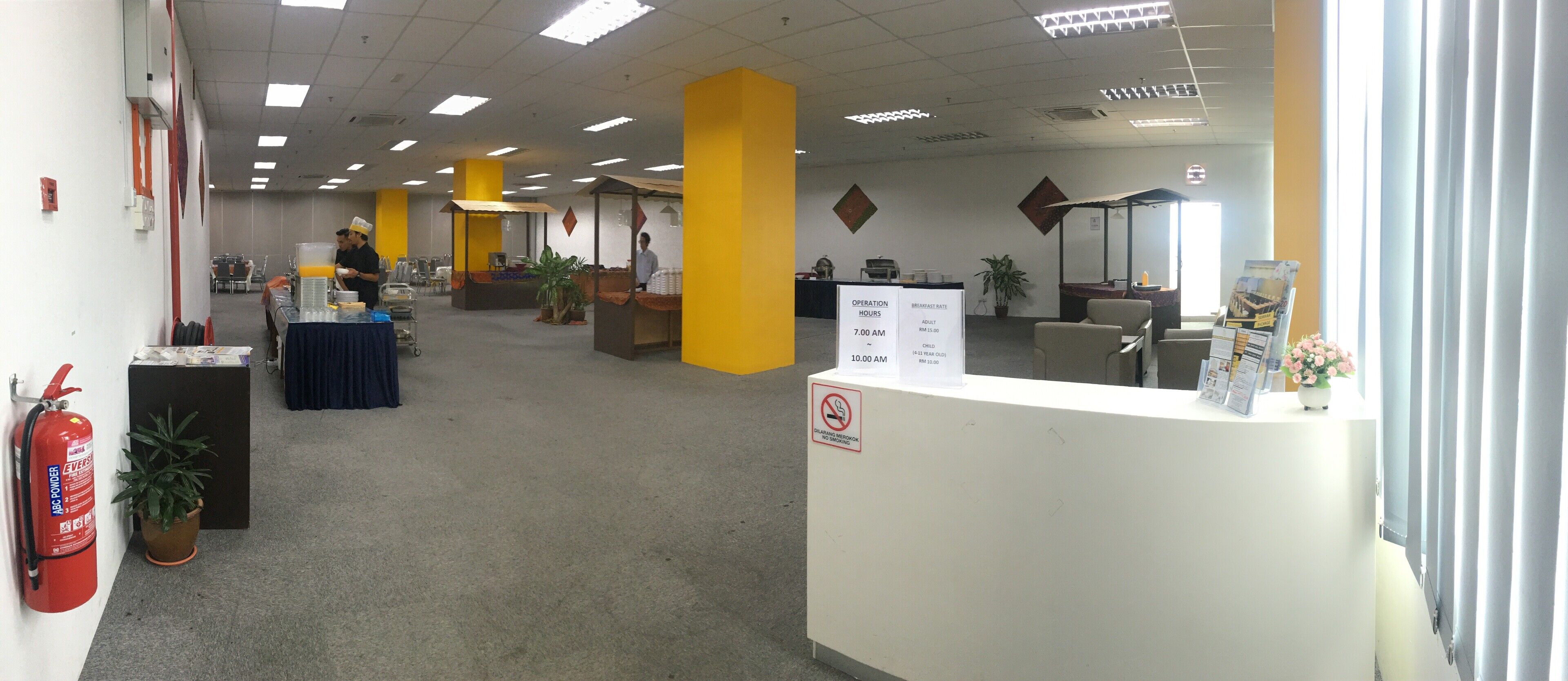 An office space with a reception desk, a fire extinguisher, and a sign indicating operation hours.