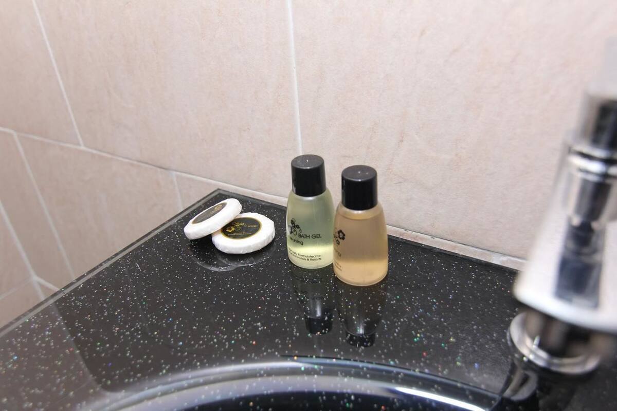 A bathroom counter with two bottles of bath gel and a pair of white bath sponges.