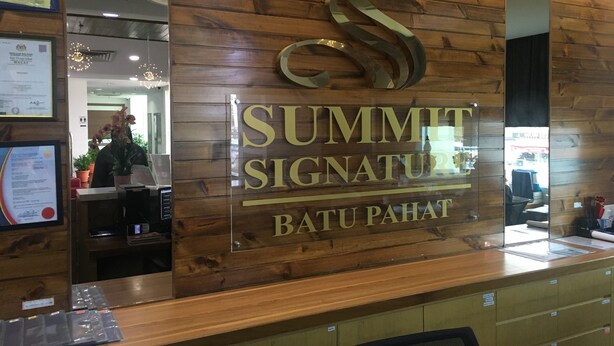 A wooden reception desk with a large 'S' logo and the words 'SUMMIT SIGNATURE' and 'BATU PAHAT' on it. - Summit Signature Hotel Batu Pahat (Batu Pahat)
