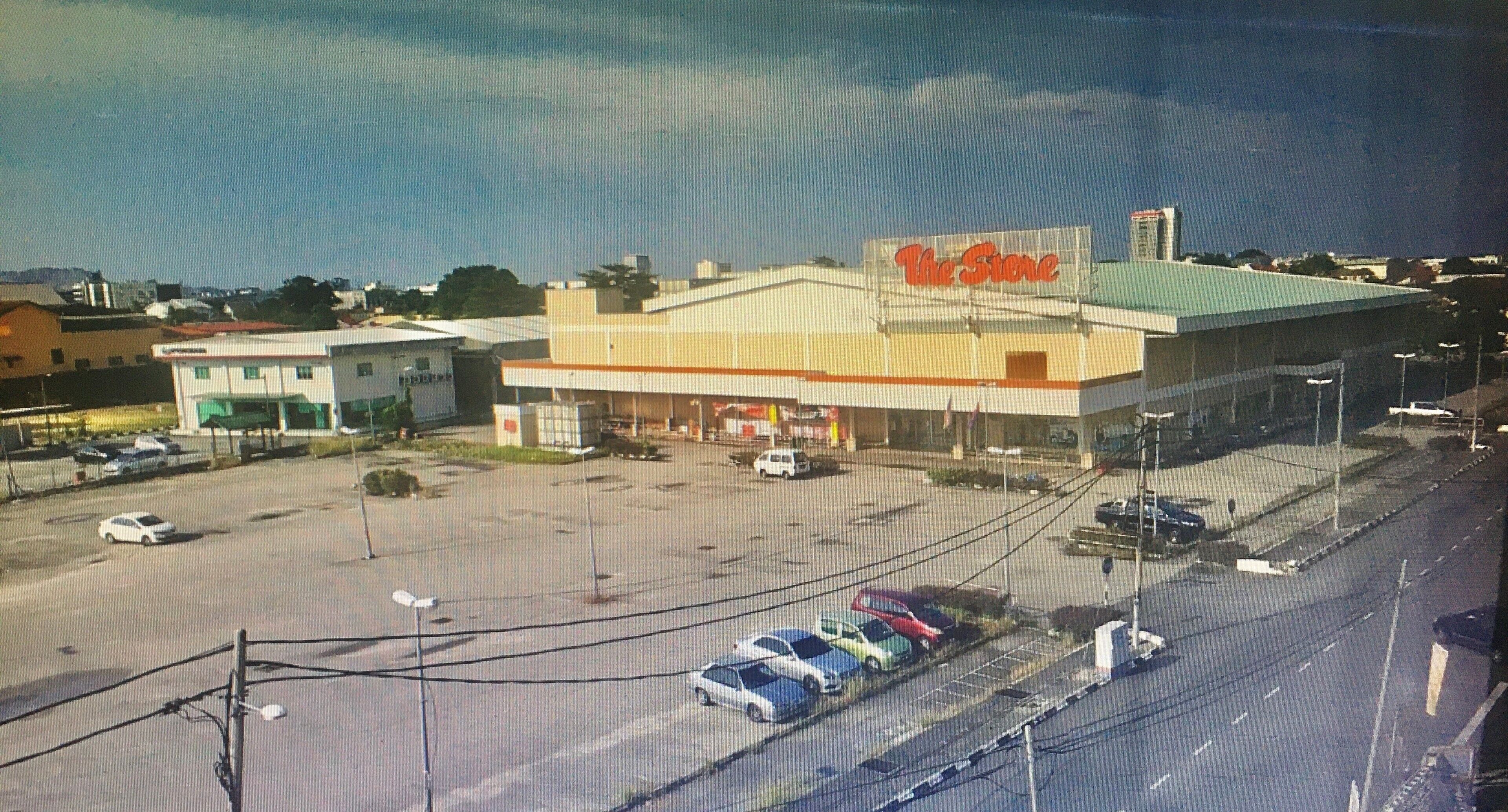 A large building with a sign reading "The Store" and a parking lot with several cars.