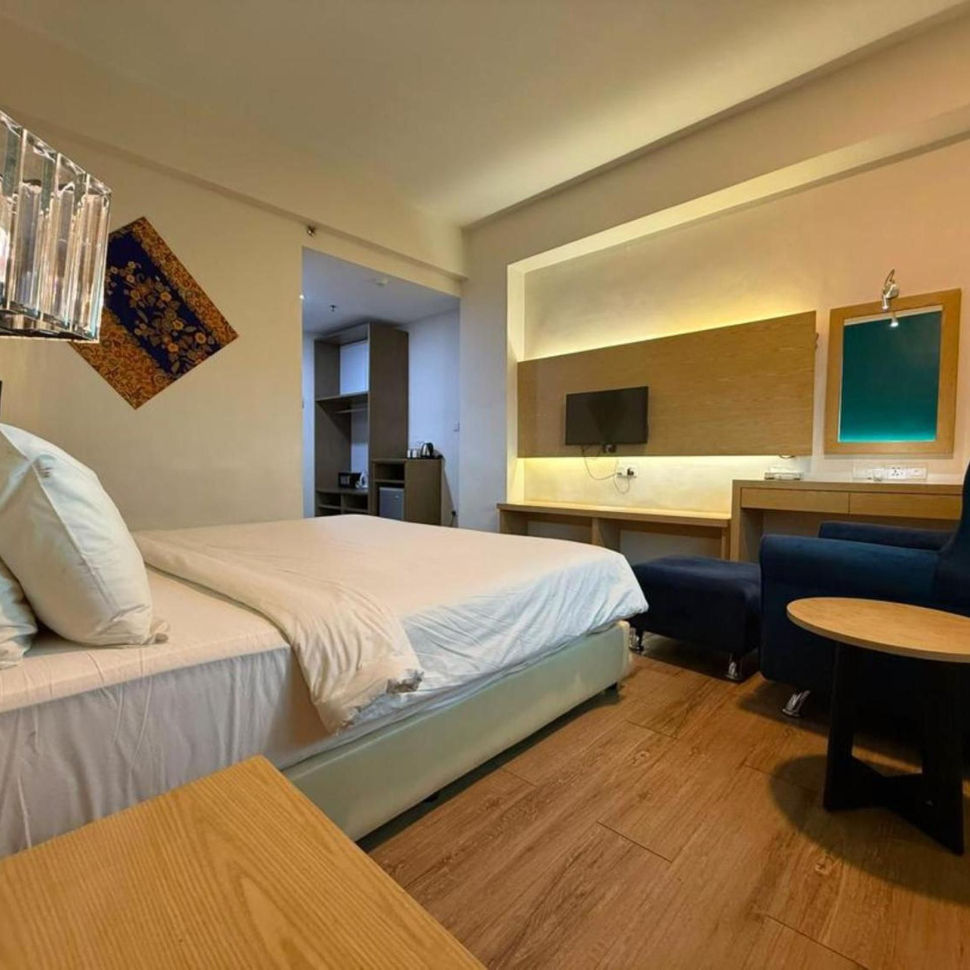 A hotel room with a bed, a desk, a chair, and a TV.