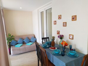 Un comedor con una mesa preparada para dos, vajilla azul, una piña y un florero con flores.