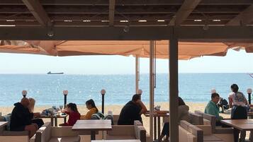 An outdoor seating area with tables and chairs, overlooking the sea.