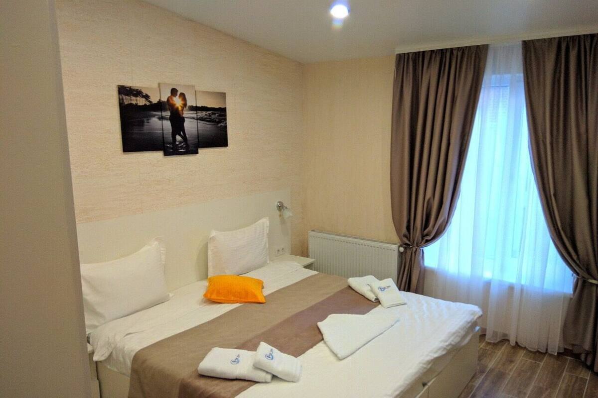 A hotel room with a large bed, white bedding, a brown striped throw, and a picture of a couple on the wall.