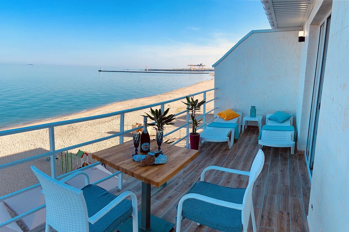 A balcony with a wooden table, two chairs, and a potted plant.