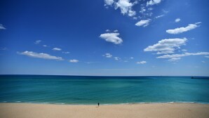 Une plage avec une eau d’un bleu limpide et un rivage sablonneux.