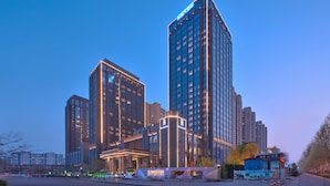 A modern hotel with a prominent entrance, multiple floors, and illuminated windows. - Taishan Blossom Hotel (Tai'an)