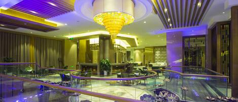 A spacious lobby with a central seating area, a glass railing, and a decorative chandelier.