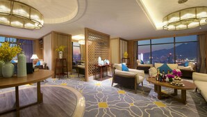 A spacious hotel room with a large window offering a city view, a round table with a vase of flowers, and a sofa with a decorative screen. - Taishan Blossom Hotel (Tai'an)