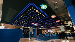 A modern interior with a geometric ceiling design, seating areas, and a bar. - Yooma Urban Lodge Tour Eiffel (Paris)