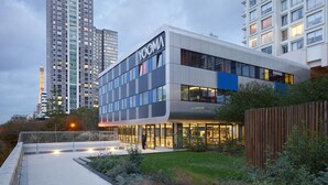 A modern building with the name "YOOMA" on the facade, surrounded by greenery and a pathway. - Yooma Urban Lodge Tour Eiffel (Paris)