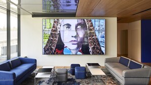A modern living room with a large digital art display, two sofas, a coffee table, and ottomans. - Yooma Urban Lodge Tour Eiffel (Paris)