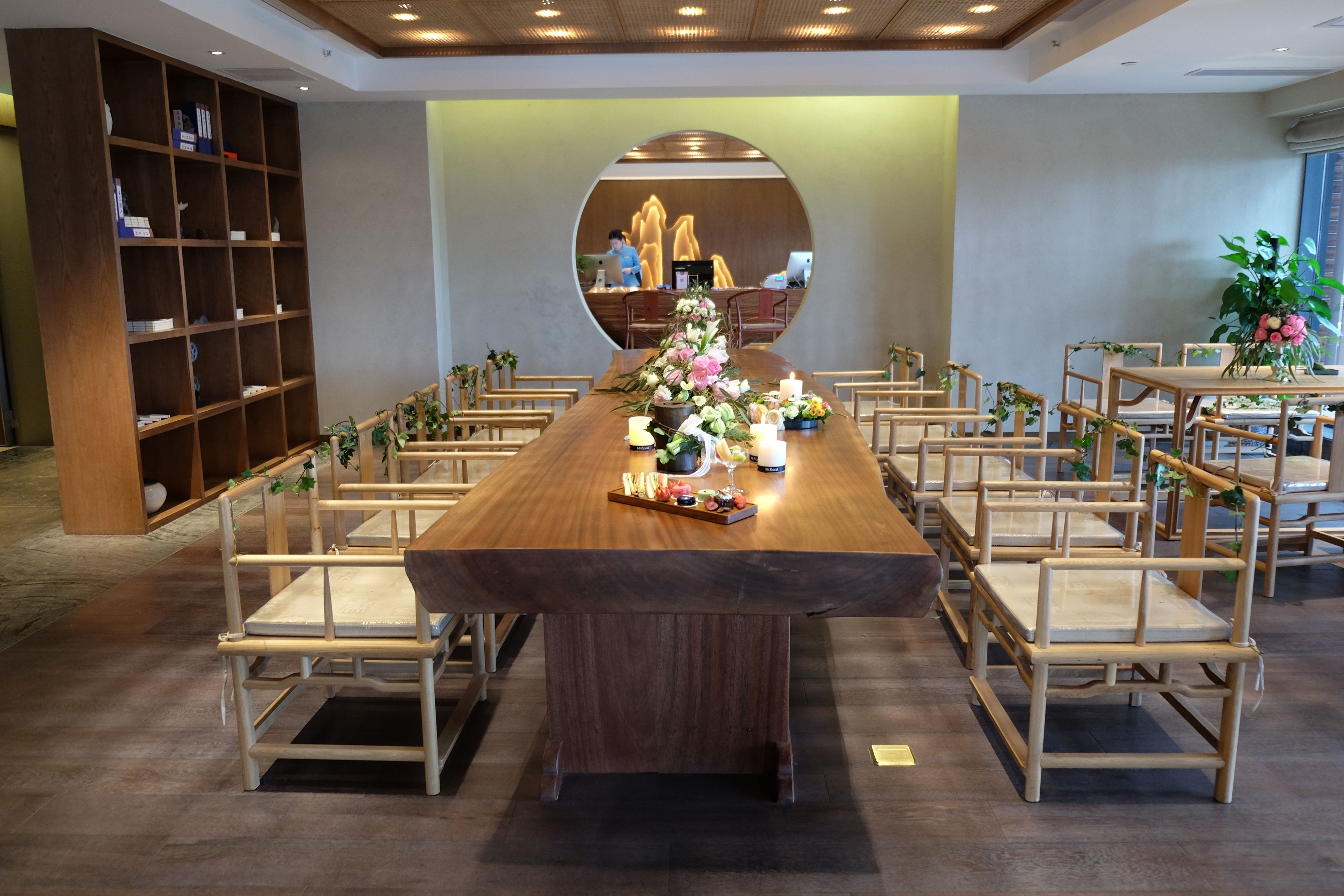 A long wooden table with chairs, a bookshelf, and a decorative centerpiece.
