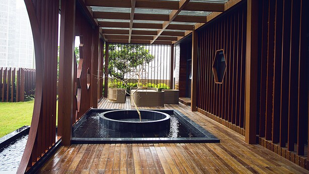 A covered outdoor area with a wooden deck, a circular water feature, and seating. - Blossom  Tao Hotel （Hangzhou Olympic Center） (Hangzhou)
