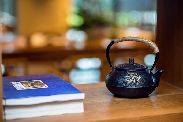 A black teapot with a bamboo handle on a wooden table next to a blue book.