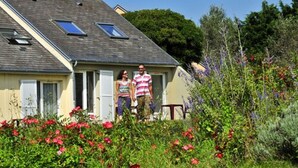 A house with a sloped roof, dormer windows, and a front porch. - Village de vacances Le Sénéquet (Blainville-sur-Mer)