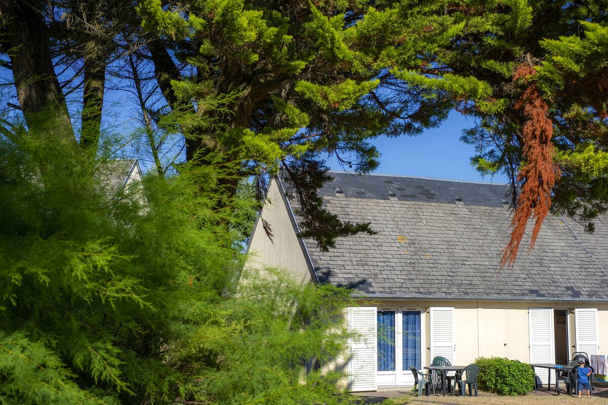 A house with a sloped roof, a small porch, and a dining area with outdoor seating.