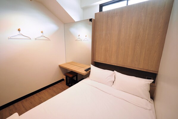 A bedroom with a bed, a wooden headboard, a bedside table, and two wall-mounted light fixtures. - T Hostel at Victory Monument (Bangkok)