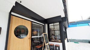 A modern cafe with a wooden door, a circular window, and a chalkboard sign. - T Hostel at Victory Monument (Bangkok)