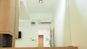 A small room with a wooden bench, a large mirror, and a door leading to another room. - T Hostel at Victory Monument (Bangkok)