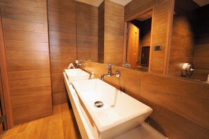 A modern bathroom with wooden paneling, a large mirror, and three sinks. - T Hostel at Victory Monument (Bangkok)