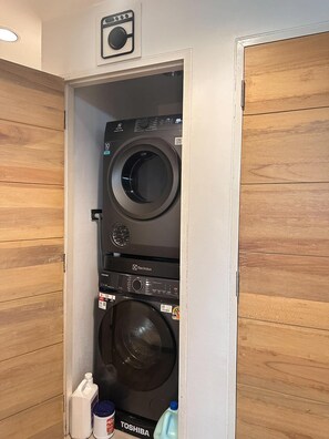 A laundry room with two stacked washing machines, a drying machine, and a water jug. - T Hostel at Victory Monument (Bangkok)