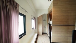 A hallway with a wooden floor, a window with curtains, and a wooden wardrobe. - T Hostel at Victory Monument (Bangkok)