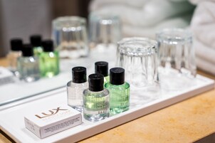 Una encimera de baño con distintos artículos de aseo, incluyendo una caja con la etiqueta 'LUX' y varias botellas de champú.