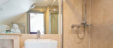 A modern bathroom with a white sink, a glass shower enclosure, and beige tiled walls.