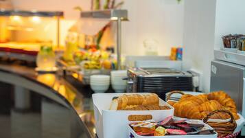 Un bufé con diversas opciones de comida, incluyendo panadería y pasteles.