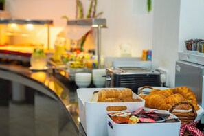 Un bufé con diversas opciones de comida, incluyendo panadería y pasteles.