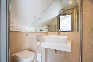 Un baño moderno con inodoro, lavamanos y ducha.