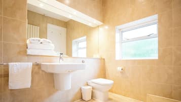 A modern bathroom with a sink, toilet, and a window providing natural light.